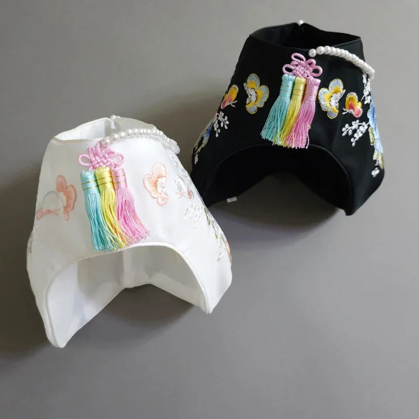 White and black Native Korean floral embroidered Jobawi hats with colorful Norigae tassels.