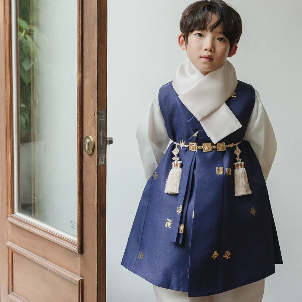 A boy wearing a navy blue Native Korean Boy Hanbok with a white scarf and gold accents.