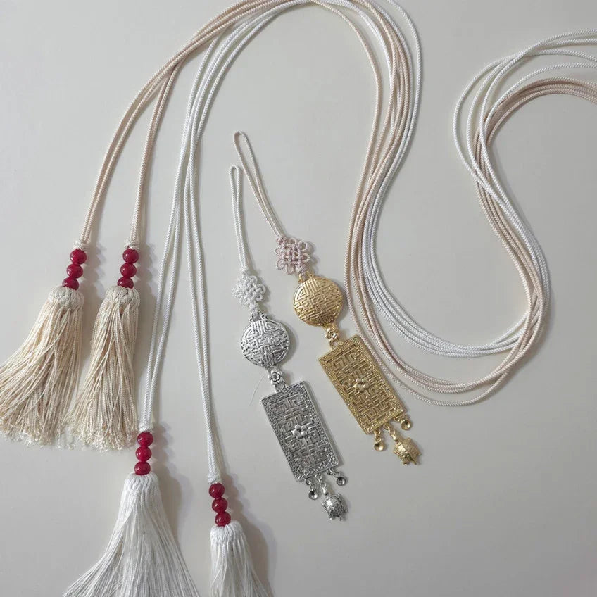 Set of traditional Korean Norigae accessories in silver, gold, and white with red beads.
