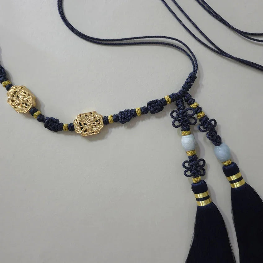 Close-up of a Native Korean navy blue Norigae tassel belt with gold ornaments.
