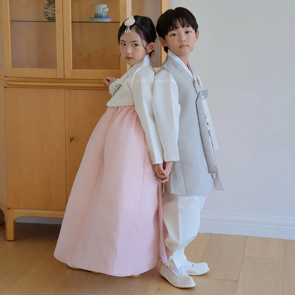 A child in a white and coral Girl Hanbok and a child in a grey Boy Hanbok by Native Korean.