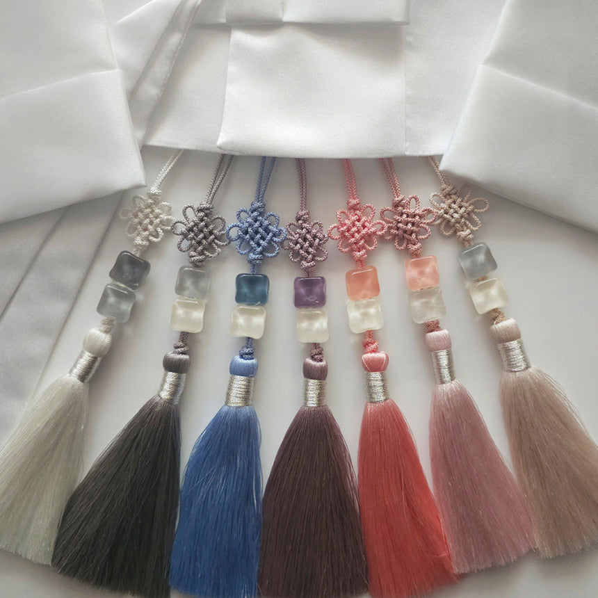 Set of colorful tassels with decorative beads on a white fabric background