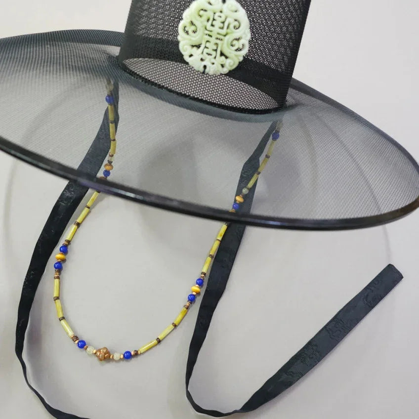 Native Korean natural stone gat string in yellow and blue on a black traditional gat