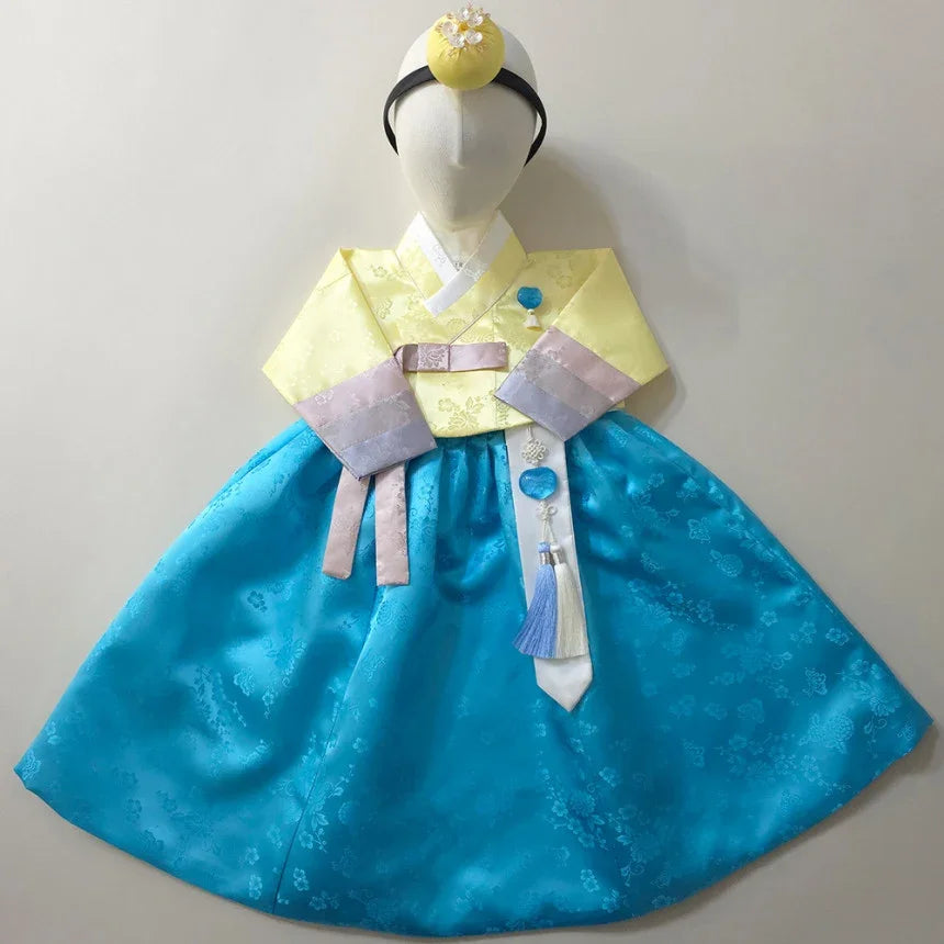 Native Korean Yunjae Girl Hanbok with a yellow jeogori, blue skirt, and norigae accessory.