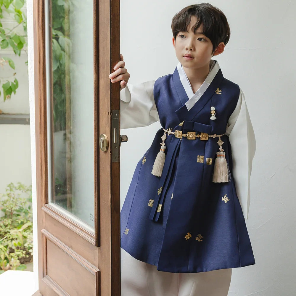 A boy wearing a navy blue and white Native Korean boy hanbok with traditional Norigae tassels.