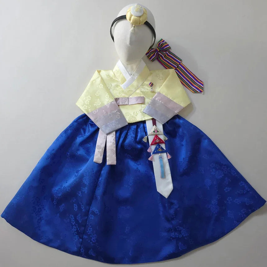 Native Korean girl hanbok featuring a yellow jeogori, blue chima, and norigae accessory.