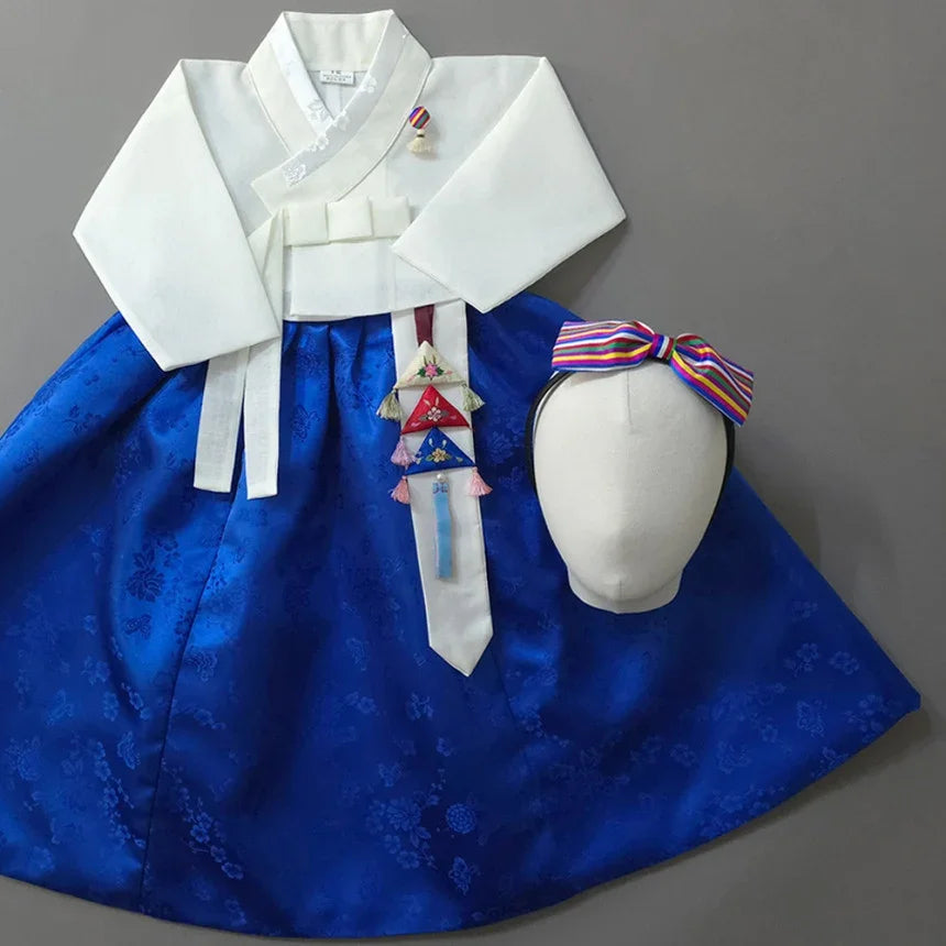 Native Korean girl hanbok with white jeogori, blue skirt, and Norigae accessory.