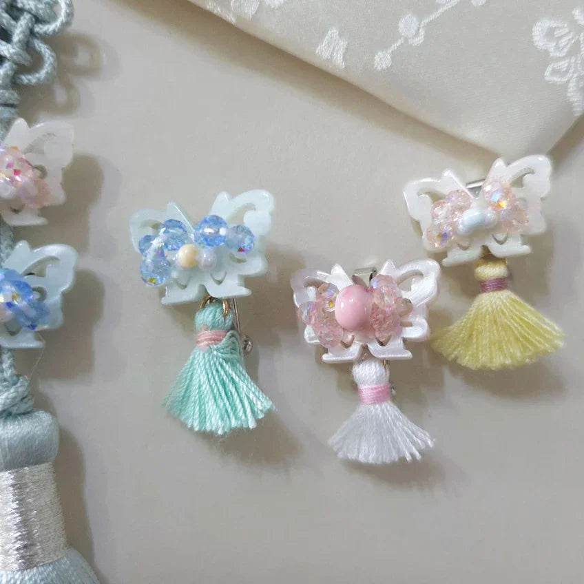 Three Native Korean crystal butterfly tassel norigae brooches in blue, pink, and yellow.