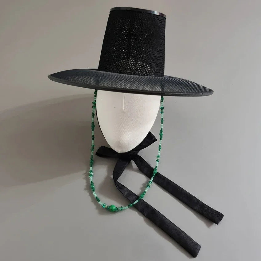 Native Korean black Gat hat with a green natural stone string on a white mannequin head.