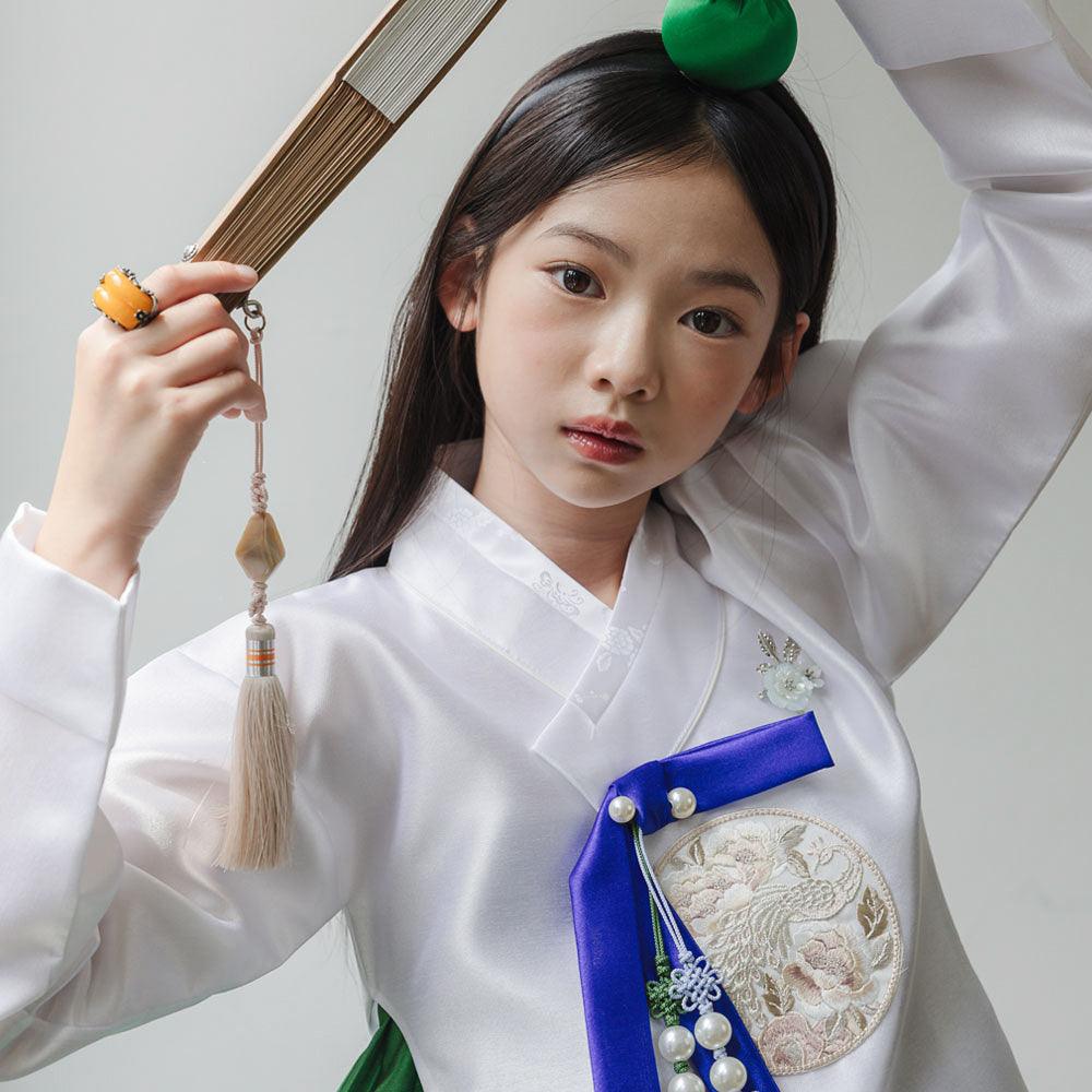 Girl wearing a white and green Native Korean Girl Hanbok with a blue ribbon and Norigae.