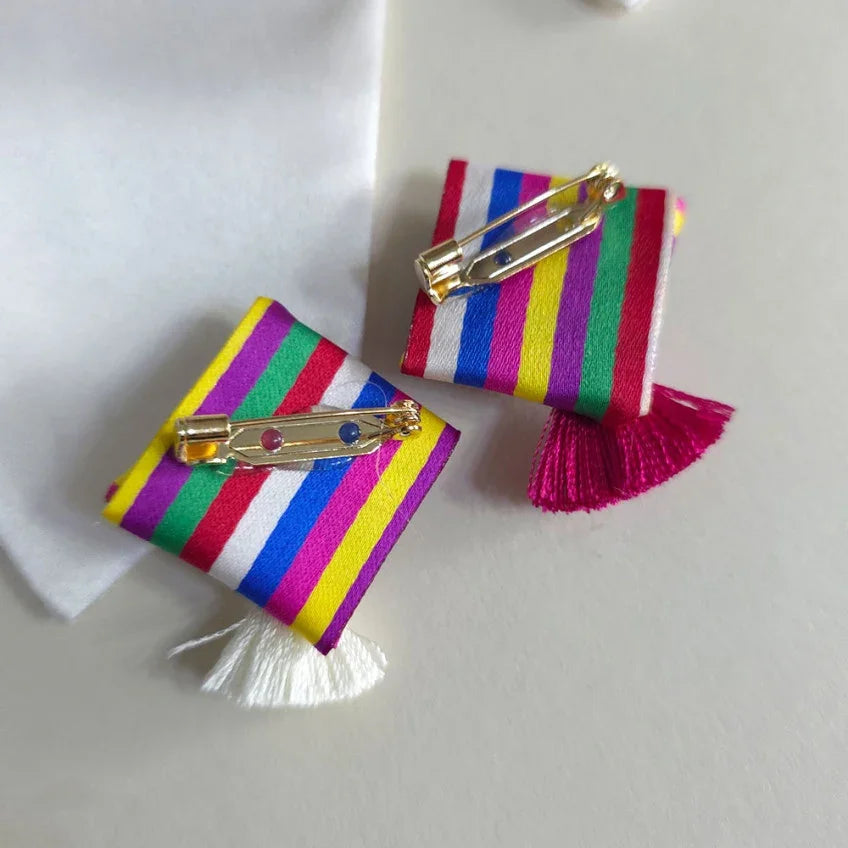 Two Native Korean Saekdong Ddakji brooches with colorful stripes and tassels.