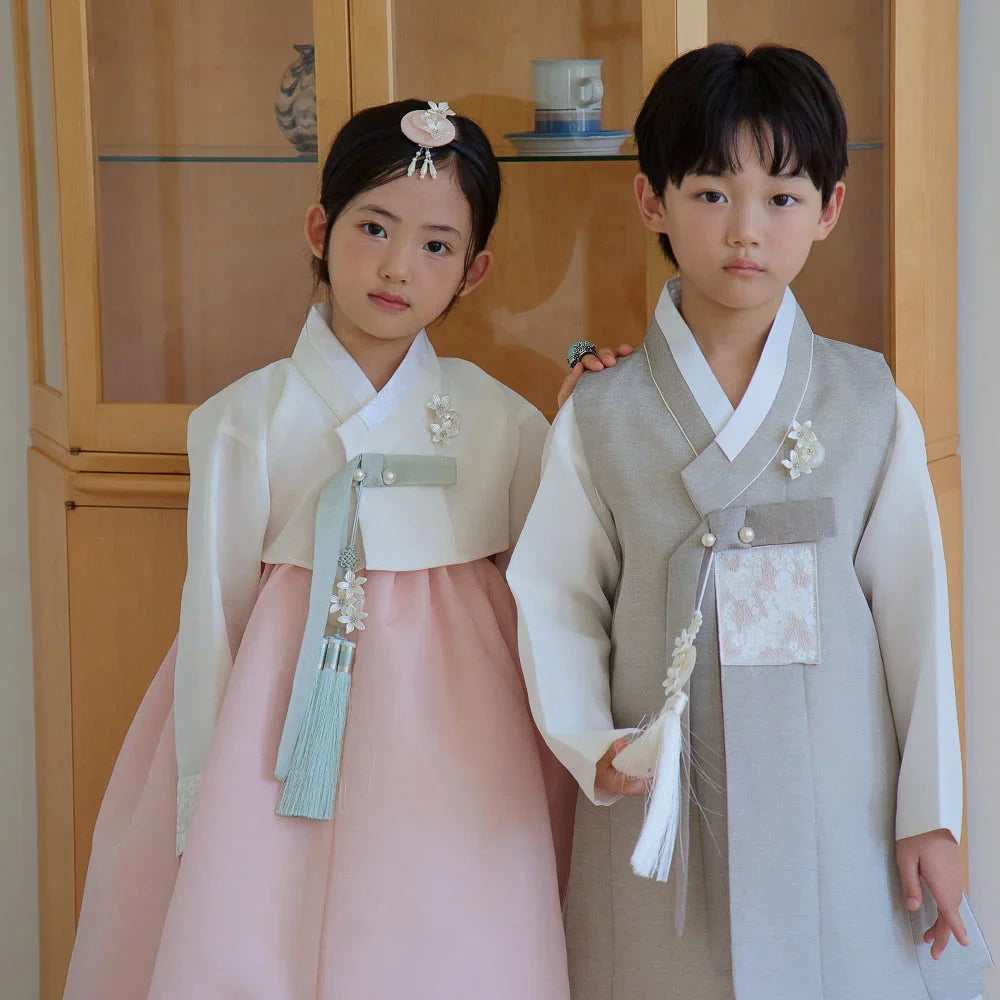 A girl in a white and pink Yujin Girl Hanbok and a boy in a grey Boy Hanbok by Native Korean.