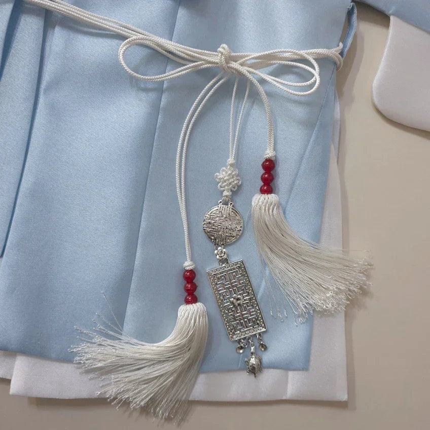 Native Korean Gunyun tassel belt with silver ornaments and white tassels on a light blue hanbok