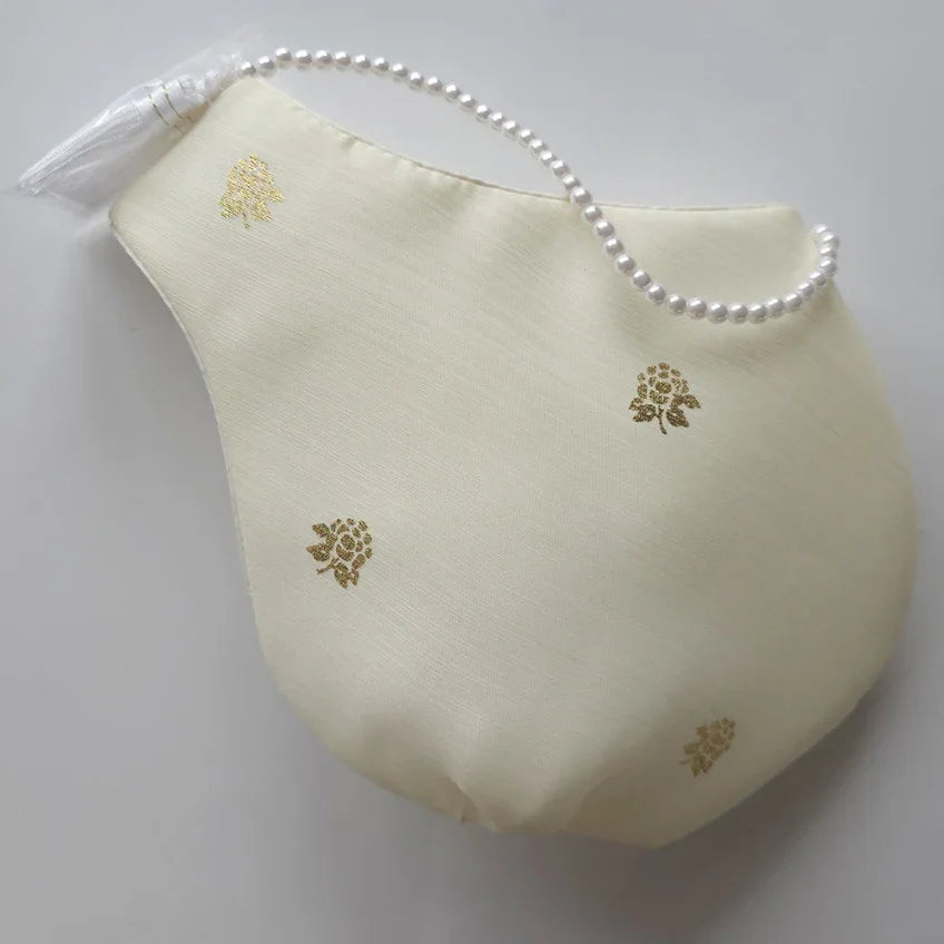 Cream-colored Korean traditional pouch with gold floral patterns and pearl strap by Native Korean