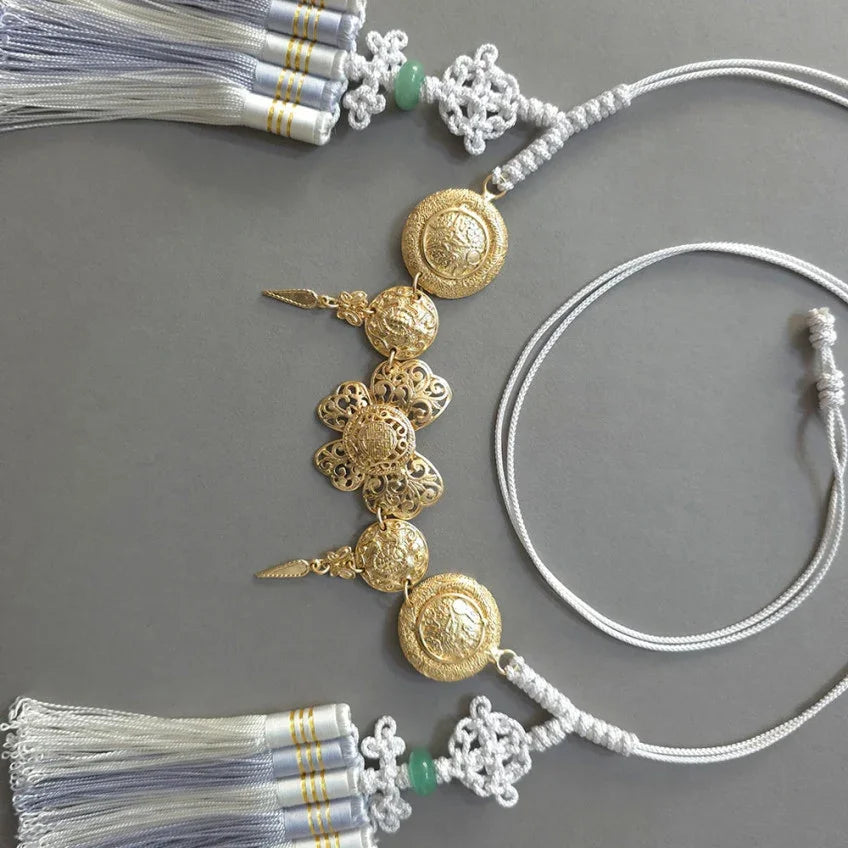 Native Korean gold medal tassel belt with intricate gold ornaments and white tassels.