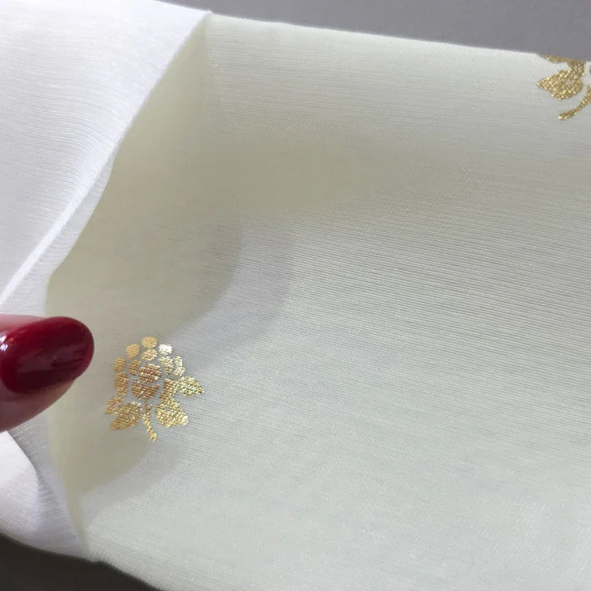Close-up of gold floral embroidery on white fabric for a Native Korean Girl Hanbok.