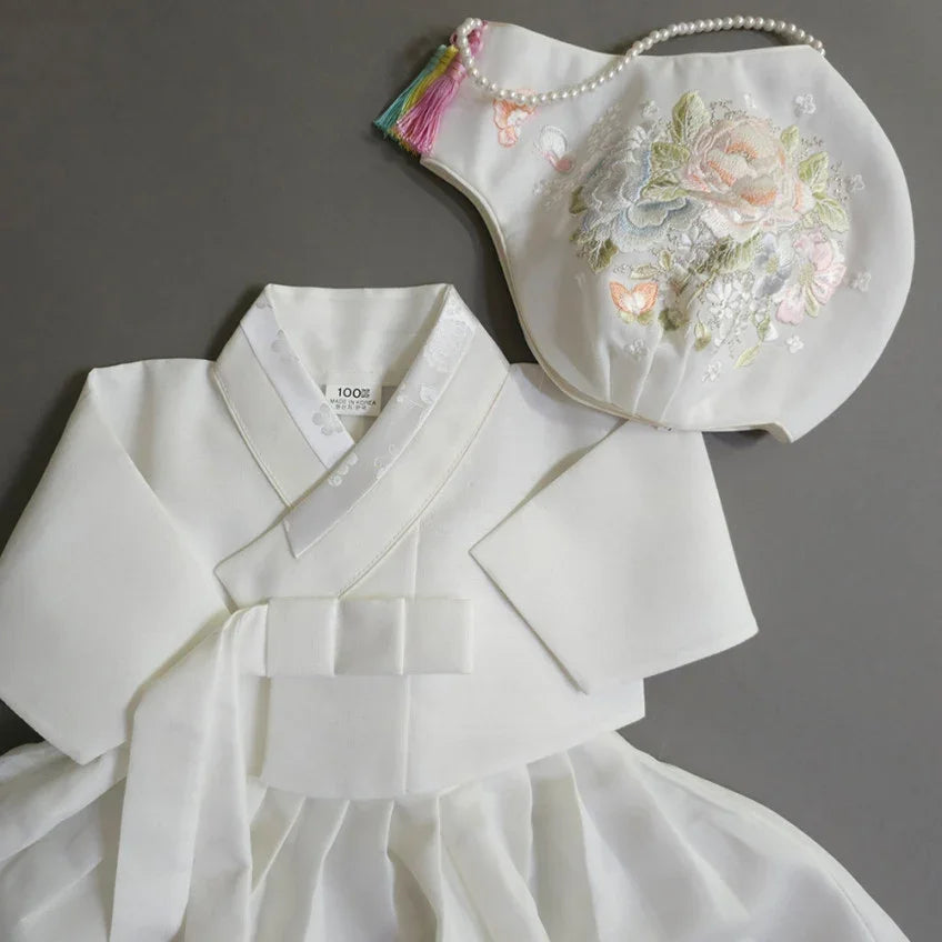 White Native Korean girl hanbok with a floral embroidered jobawi hat.