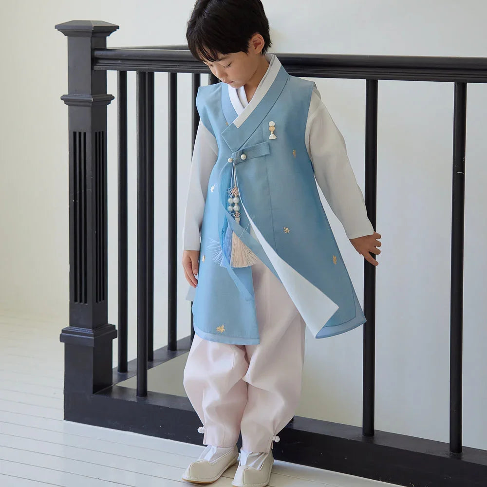 A boy wearing a sky blue and white Native Korean boy hanbok with a norigae accessory.