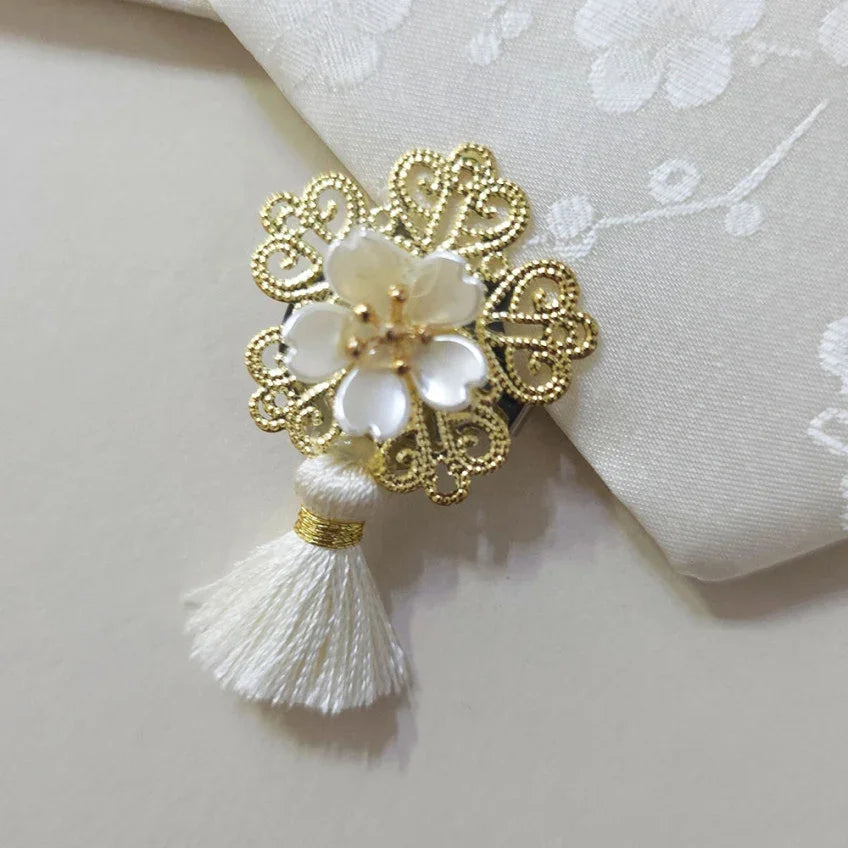 Bloom Trio Tassel Norigae by Native Korean with a gold filigree ornament and white flower.