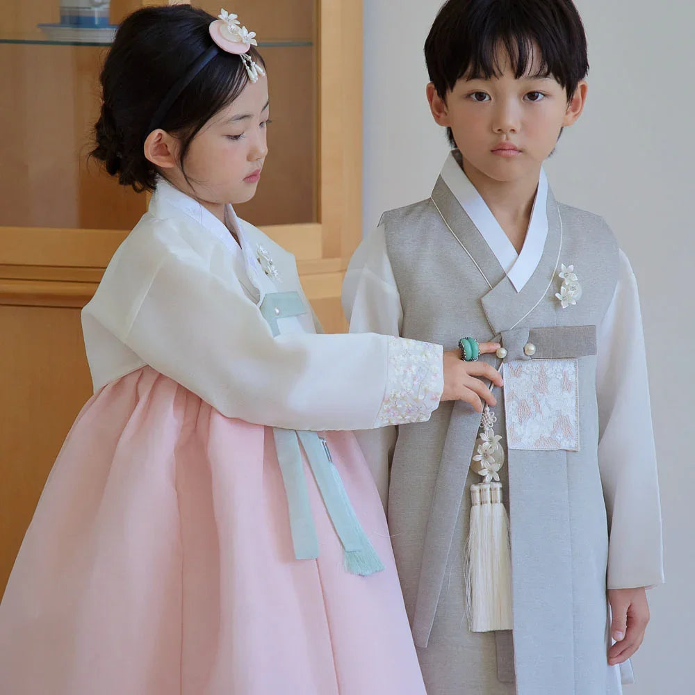 A girl in a white and pink Yujin Girl Hanbok and a boy in a grey Boy Hanbok by Native Korean.