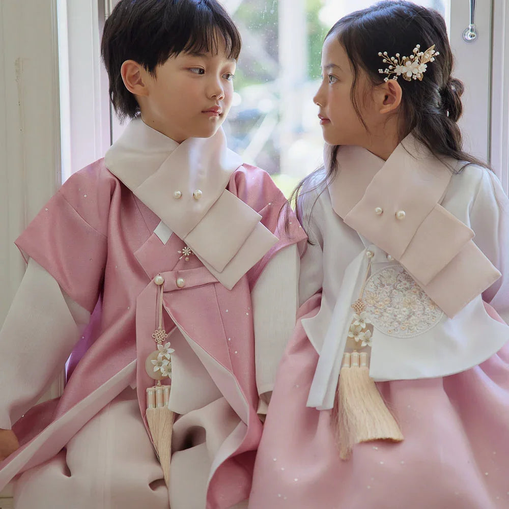 A boy and girl wearing Pearl Pink Native Korean hanbok with matching norigae accessories.