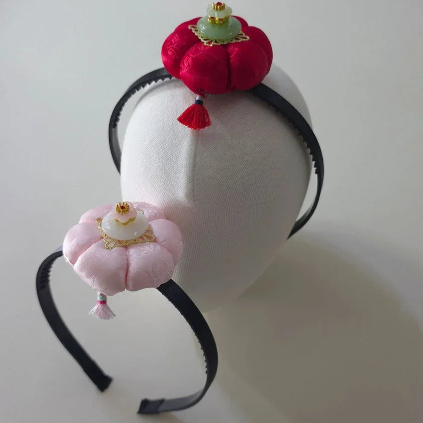 Two Native Korean Star Pumpkin headbands in red and pink on a white display head.