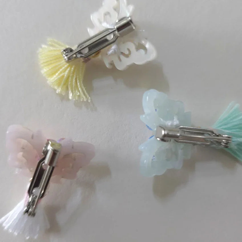 Three Native Korean crystal butterfly tassel brooches in yellow, pink, and blue.