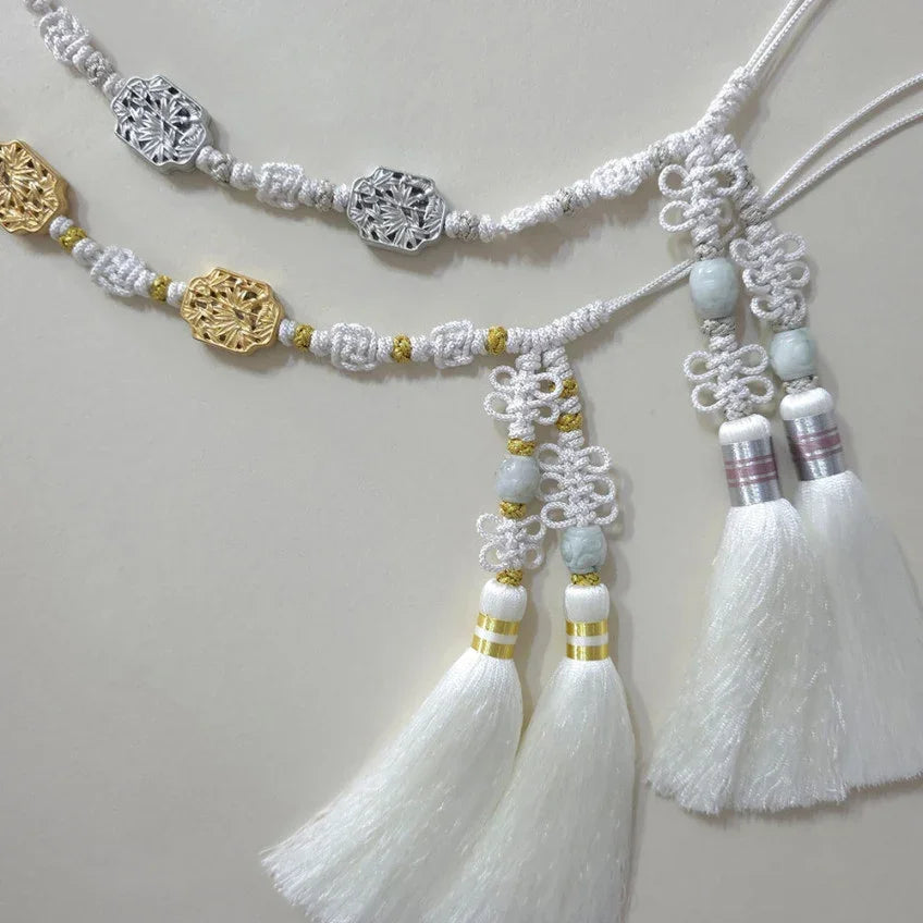Detailed view of a white Native Korean Norigae tassel belt with gold and silver ornaments.