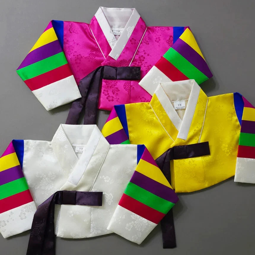 Three colorful Seunju Saekdong Jeogori in pink, yellow, and white with rainbow sleeves.