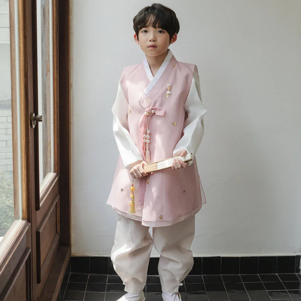 A young boy wearing a pink and white Native Korean boy hanbok with a norigae accessory.