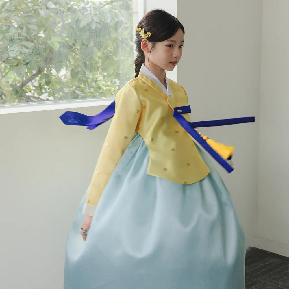 A girl wearing a Native Korean Ian yellow and sky blue girl hanbok with a Norigae.