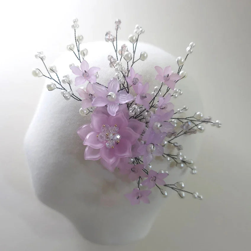 Purple floral arrangement on a mannequin head against a white background