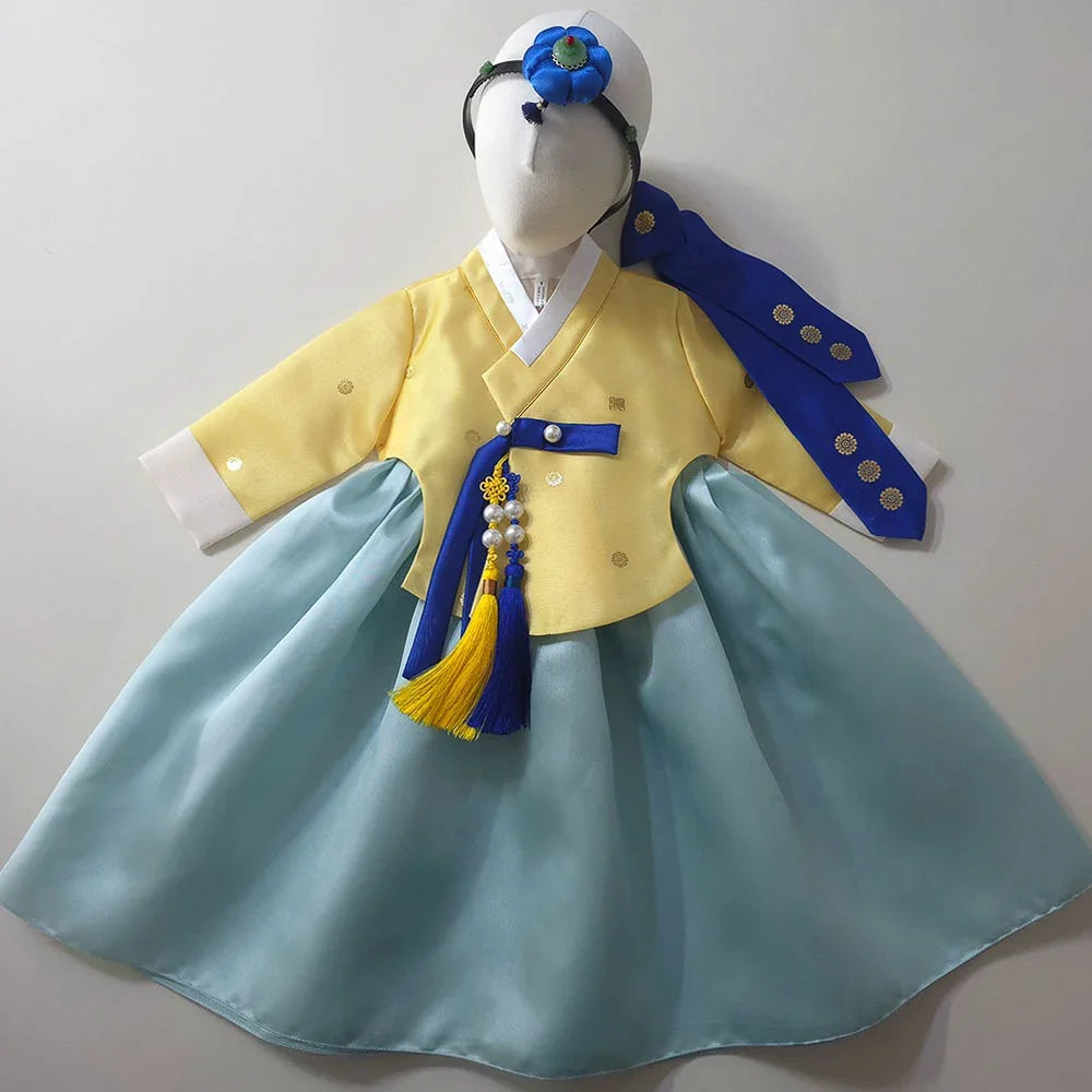 Native Korean girl hanbok in yellow and sky blue with a matching norigae and headpiece.