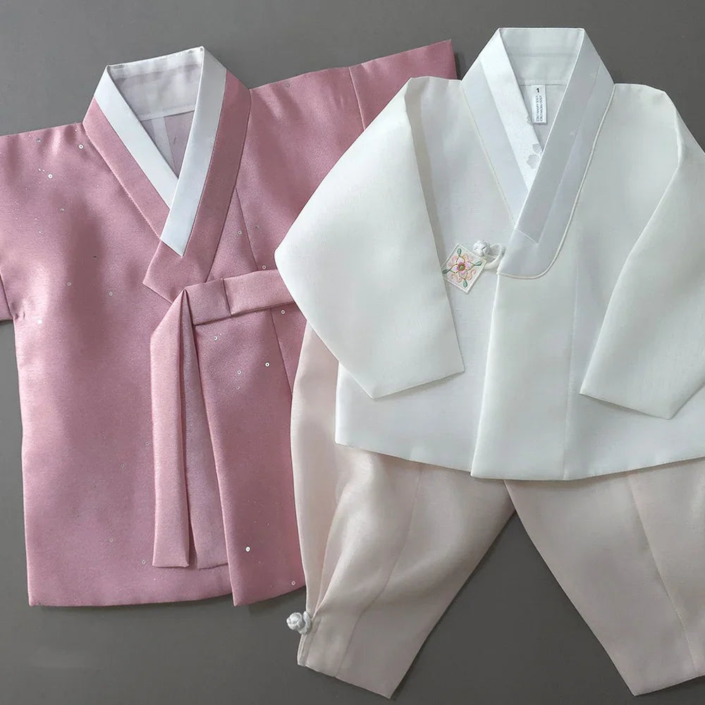 Pearl pink and white Native Korean Boy Hanbok sets laid flat on a gray background.