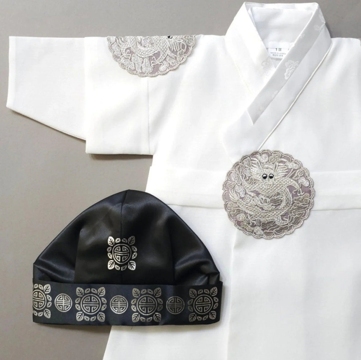 White Native Korean boy hanbok with silver dragon embroidery and a black gunmo hat.