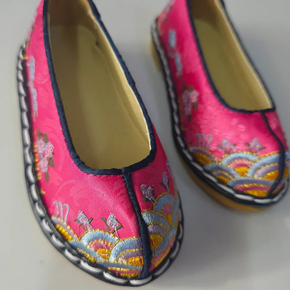 Pair of magenta Native Korean girl hanbok shoes with floral embroidery and traditional patterns