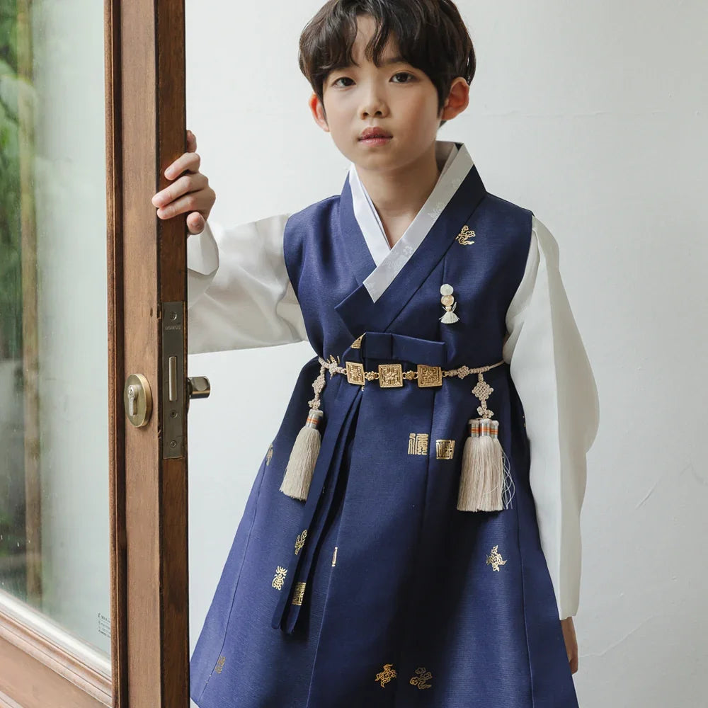 A young boy wearing a navy blue Native Korean Boy Hanbok with gold embroidery and a Norigae.