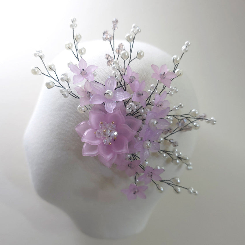 Purple floral arrangement on a mannequin head against a white background
