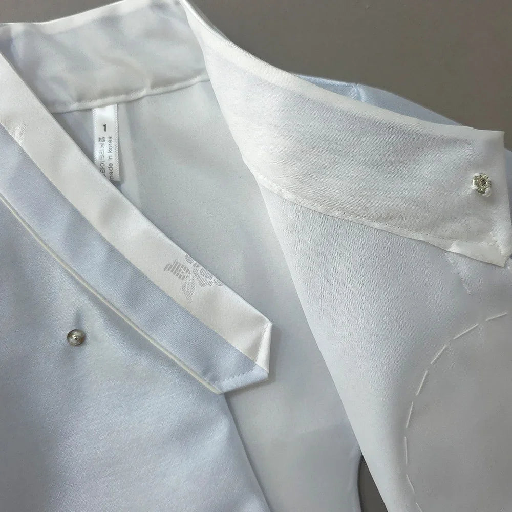 Close-up detail of a white Native Korean girl hanbok collar with pearl buttons.