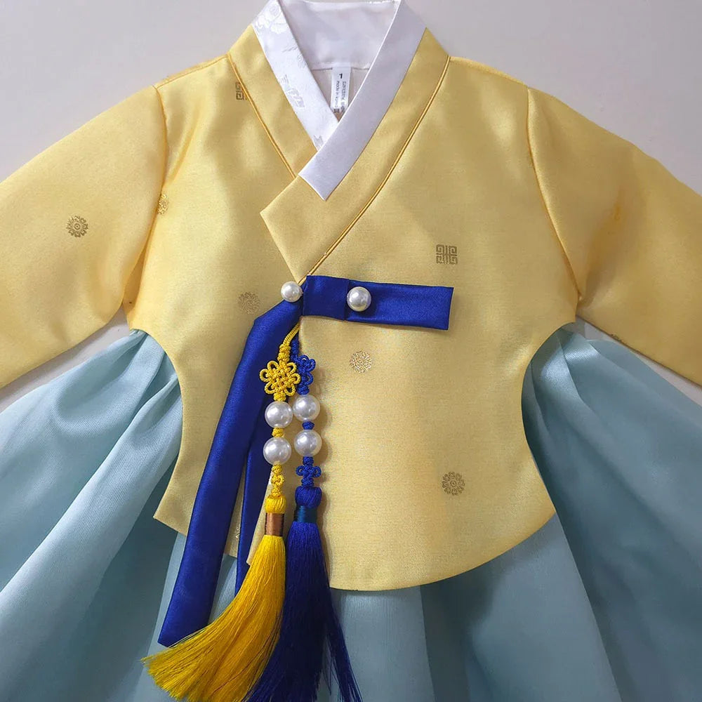 Yellow and light blue Girl Hanbok by Native Korean featuring a blue ribbon and Norigae accessory.